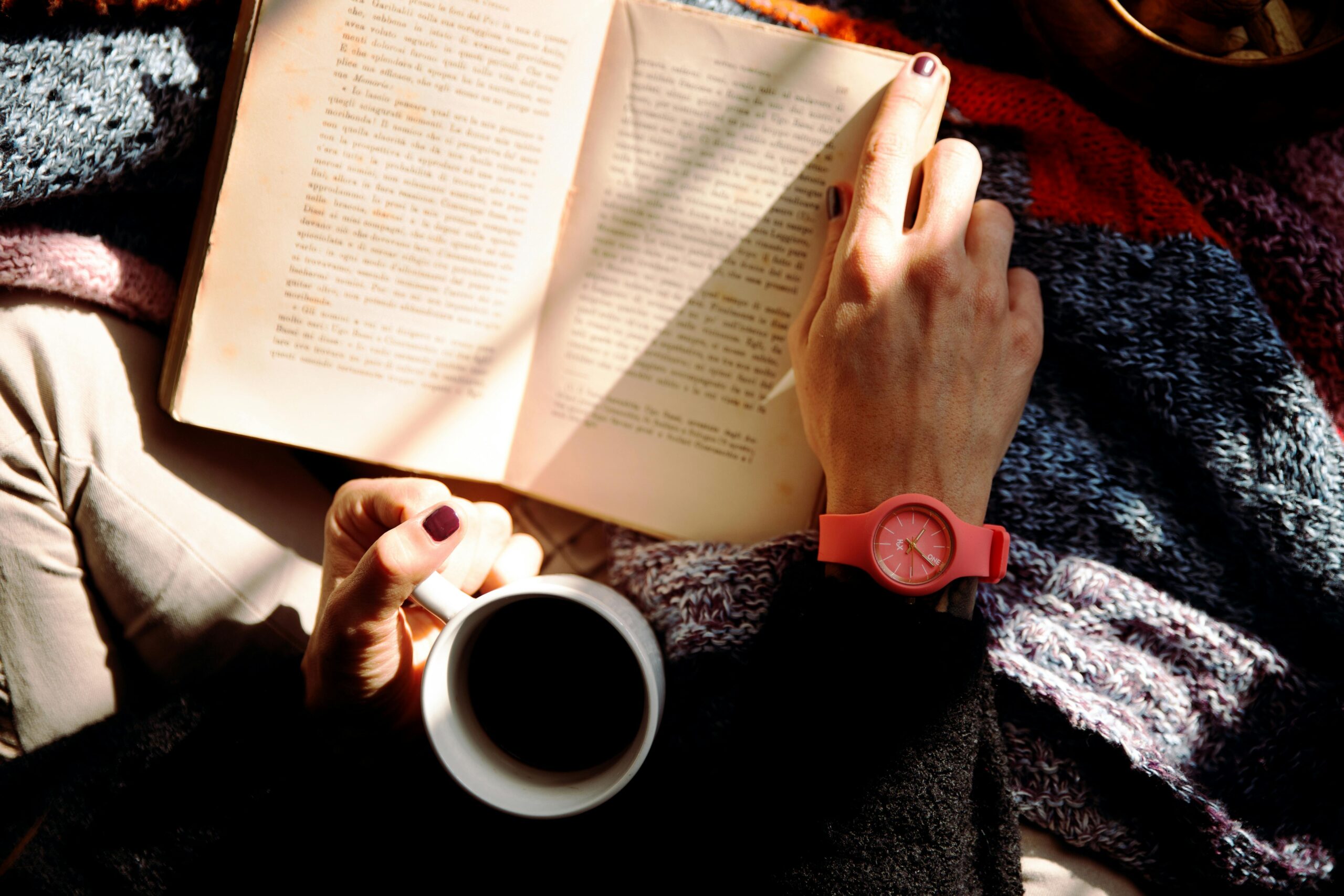 Photo by Vincenzo Malagoli: https://www.pexels.com/photo/person-reading-book-and-holding-coffee-1550648/